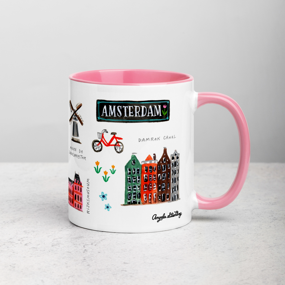 White ceramic coffee mug with pink handle and inside; has Amsterdam illustration by Angela Staehling