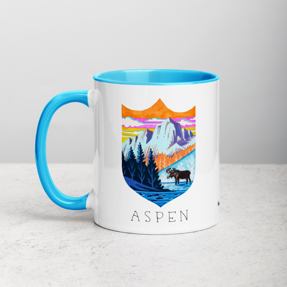 White ceramic coffee mug with blue handle and inside; has Aspen Colorado illustration by Angela Staehling