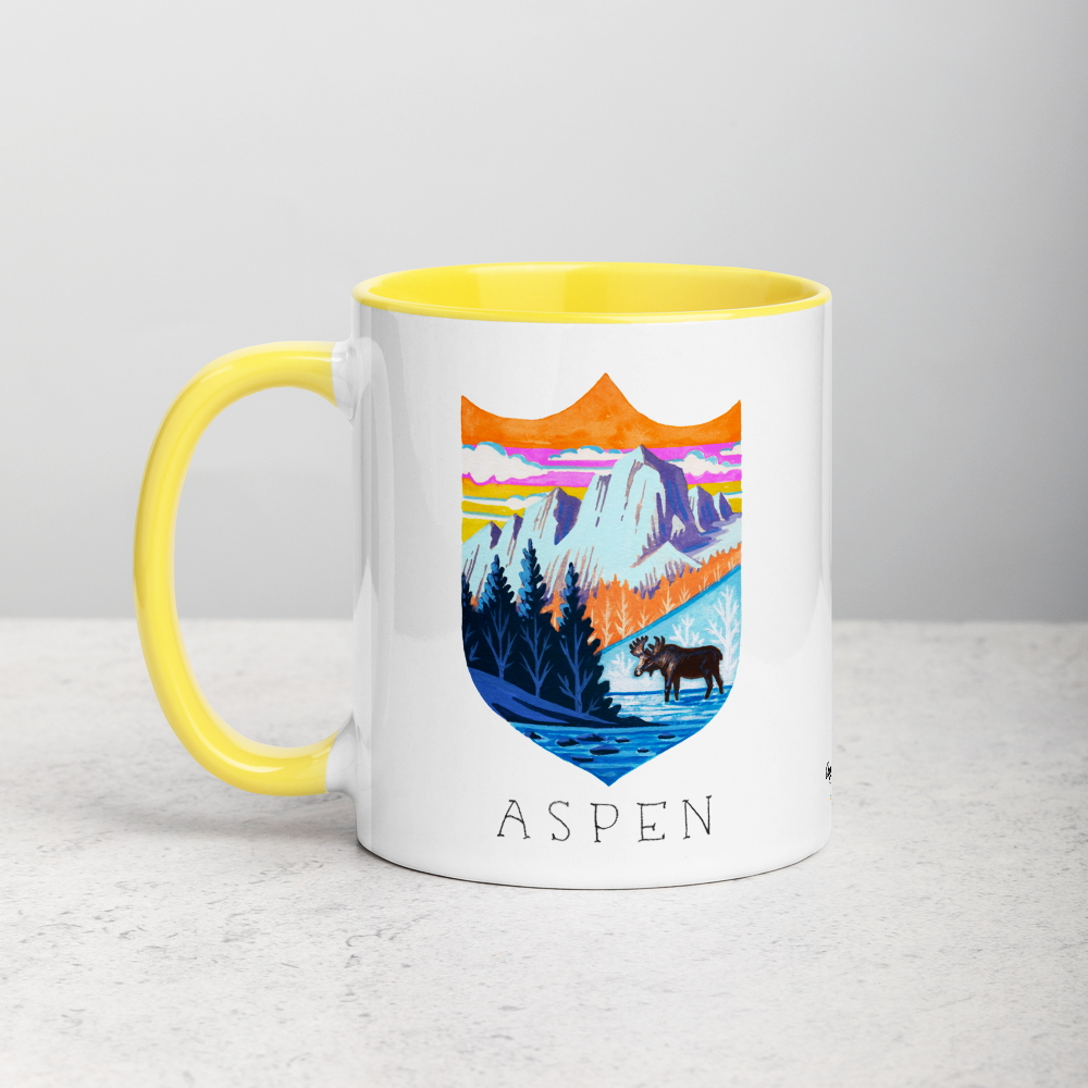 White ceramic coffee mug with yellow handle and inside; has Aspen Colorado illustration by Angela Staehling