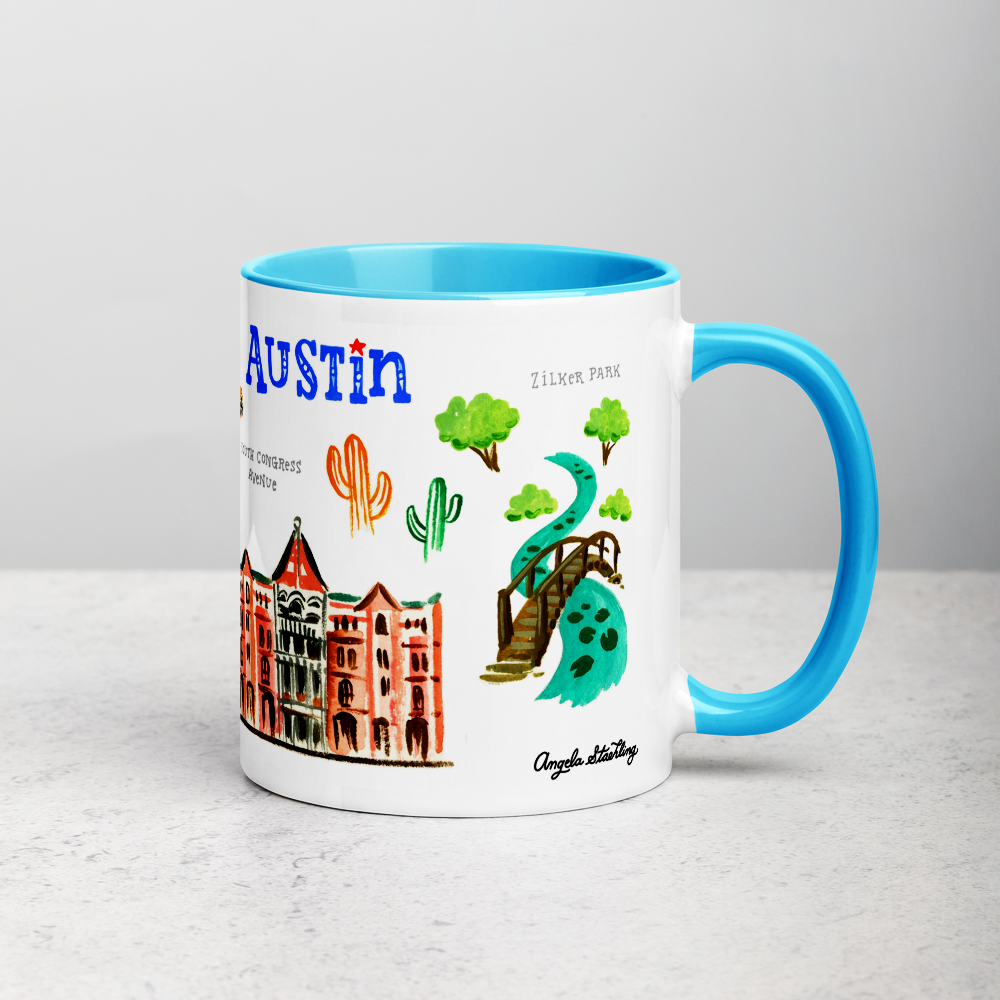 White ceramic coffee mug with blue handle and inside; has Austin landmarks illustration by Angela Staehling