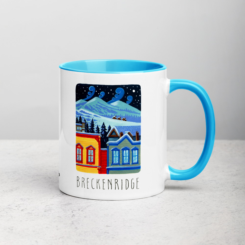 White ceramic coffee mug with blue handle and inside; has Breckenridge illustration by Angela Staehling