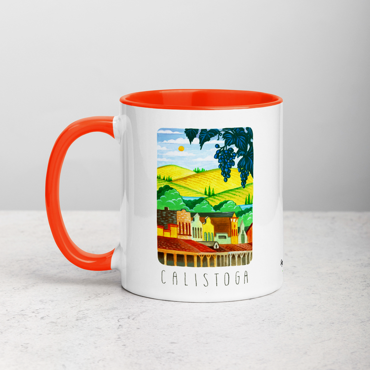 White ceramic coffee mug with orange handle and inside; has Calistoga California illustration by Angela Staehling