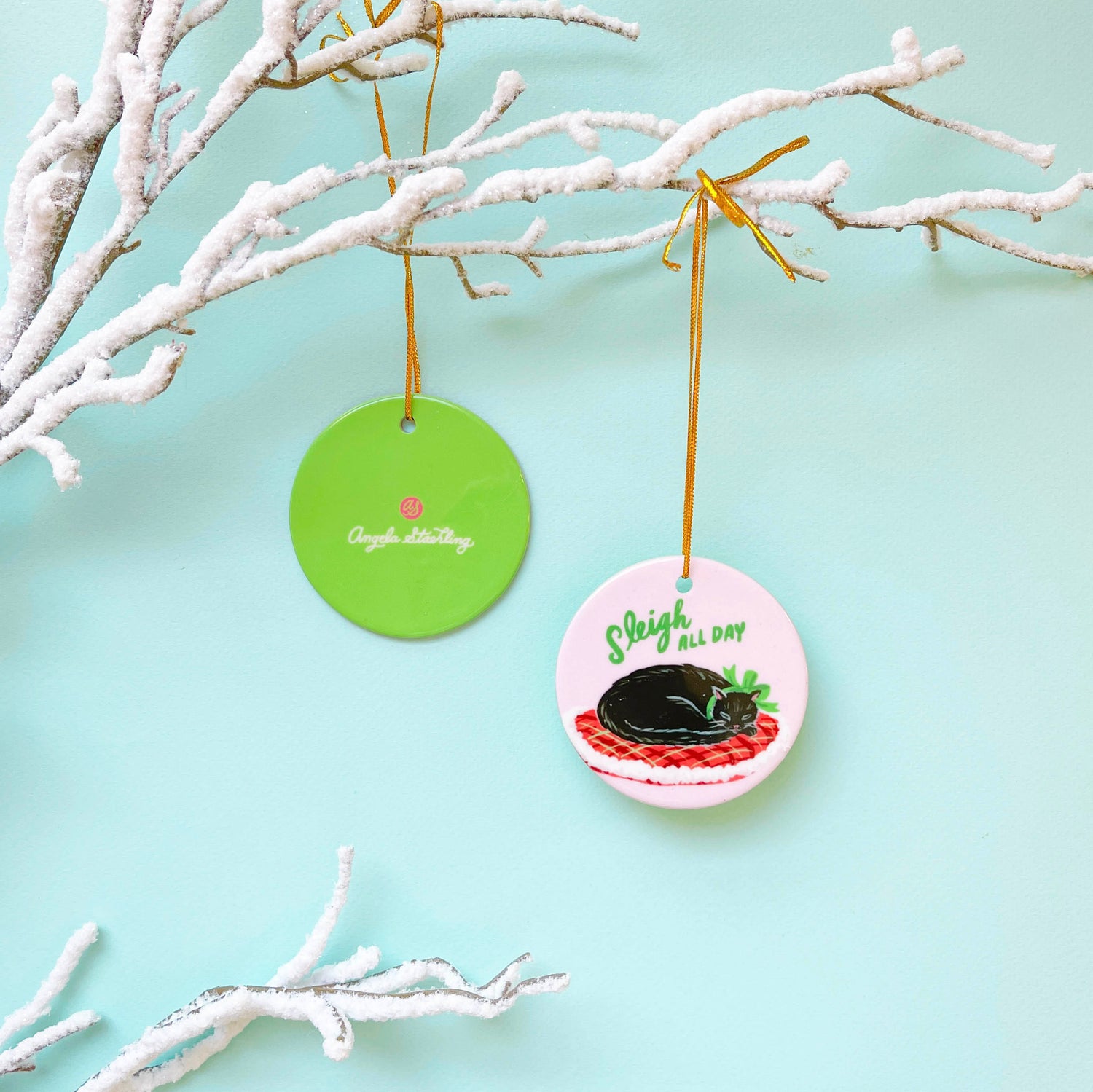 Black cat porcelain Christmas ornament wearing Christmas ribbon hanging from snowy branch