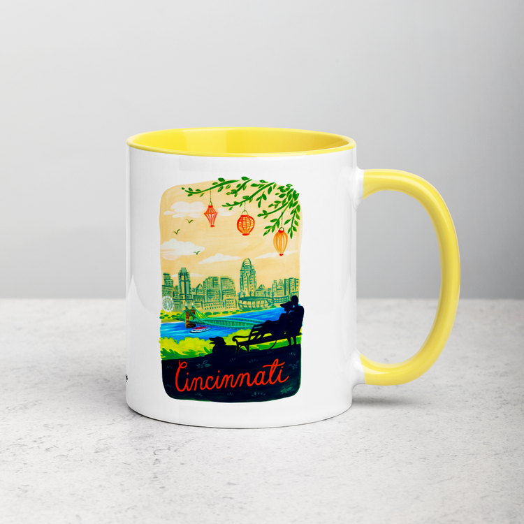 White ceramic coffee mug with yellow handle and inside; has Cincinnati Ohio illustration by Angela Staehling