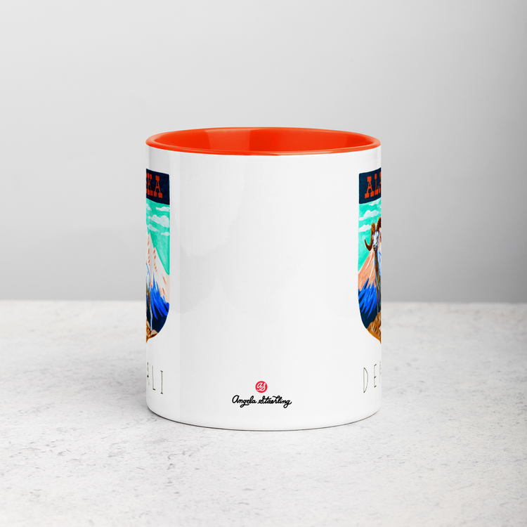 White ceramic coffee mug with orange handle and inside; has Denali National Park illustration by Angela Staehling