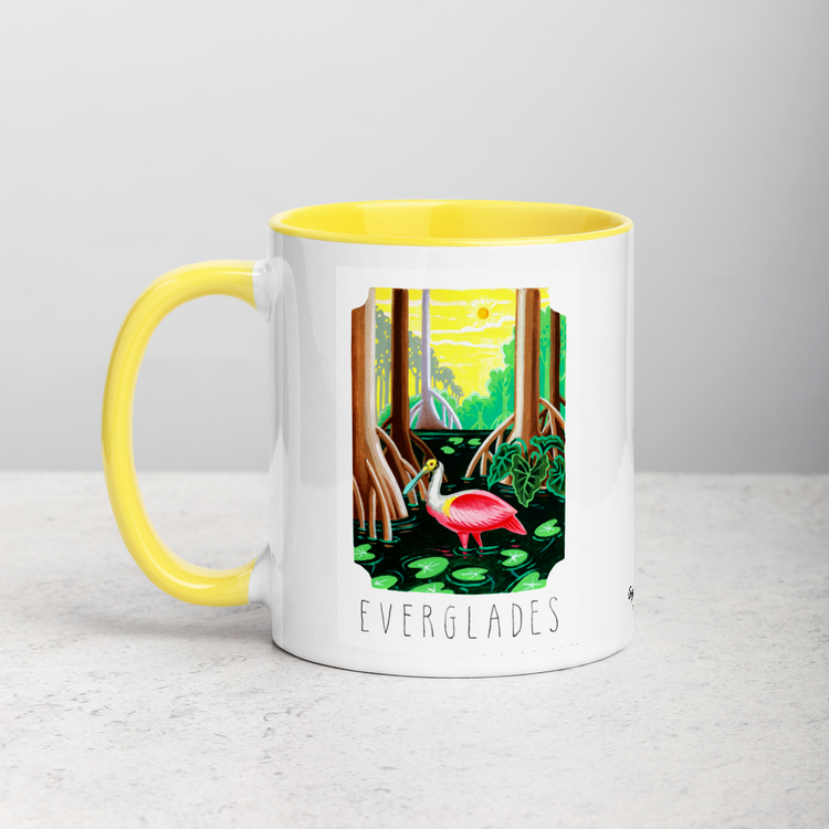White ceramic coffee mug with yellow handle and inside; has Everglades National Park illustration by Angela Staehling
