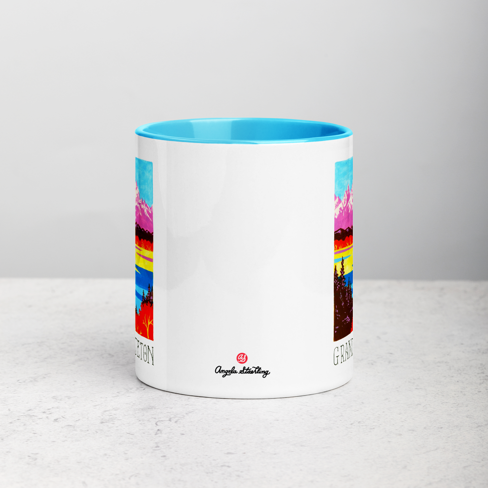 White ceramic coffee mug with blue handle and inside; has Grand Teton National Park illustration by Angela Staehling