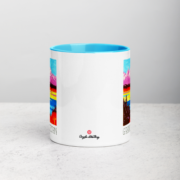 White ceramic coffee mug with blue handle and inside; has Grand Teton National Park illustration by Angela Staehling
