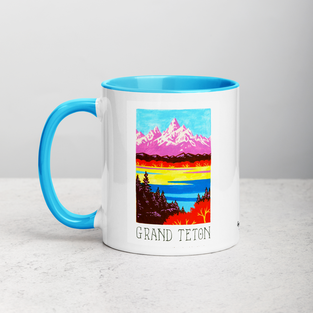 White ceramic coffee mug with blue handle and inside; has Grand Teton National Park illustration by Angela Staehling