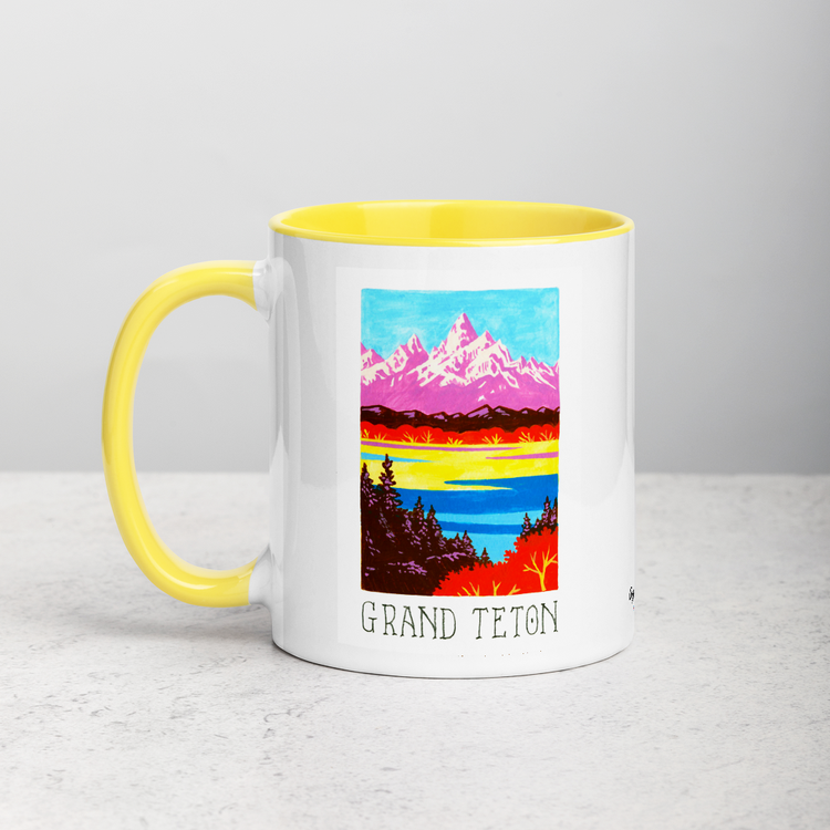 White ceramic coffee mug with yellow handle and inside; has Grand Teton National Park illustration by Angela Staehling