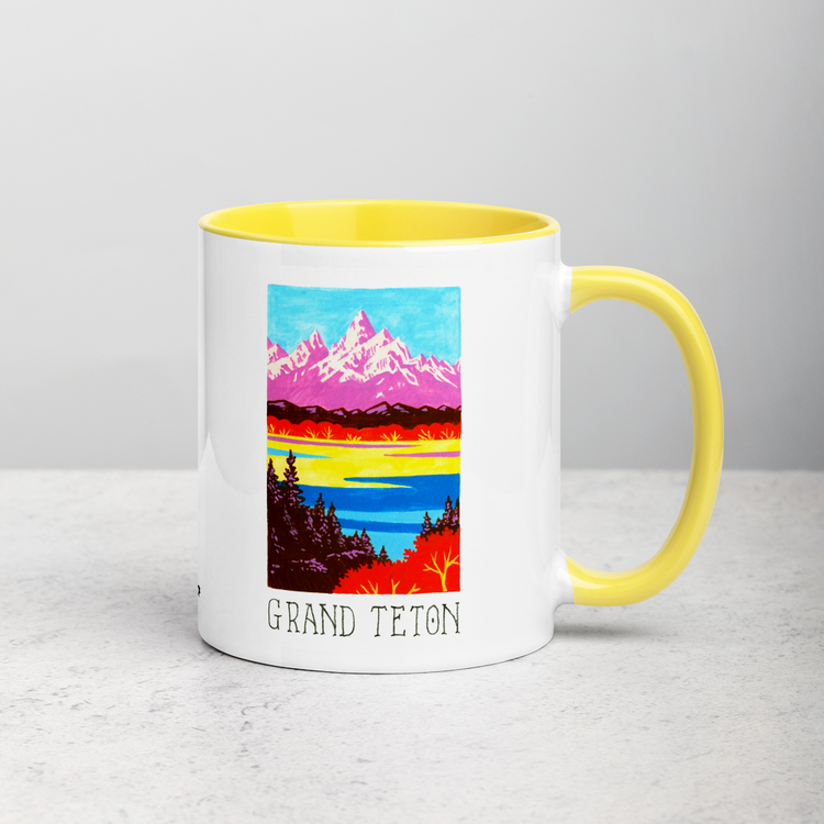 White ceramic coffee mug with yellow handle and inside; has Grand Teton National Park illustration by Angela Staehling