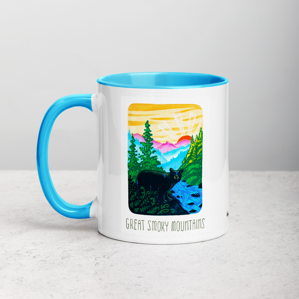 White ceramic coffee mug with blue handle and inside; has Great Smoky Mountains National Park illustration by Angela Staehling