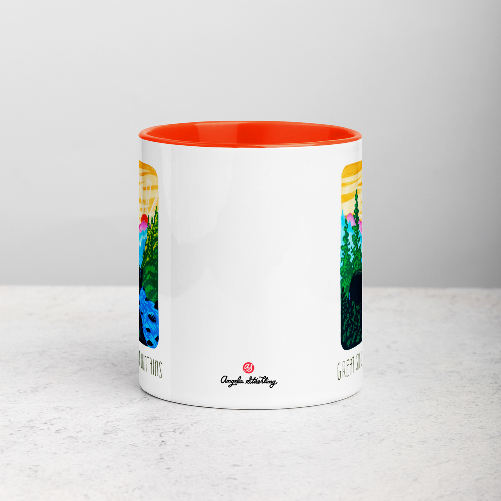 White ceramic coffee mug with orange handle and inside; has Great Smoky Mountains National Park illustration by Angela Staehling
