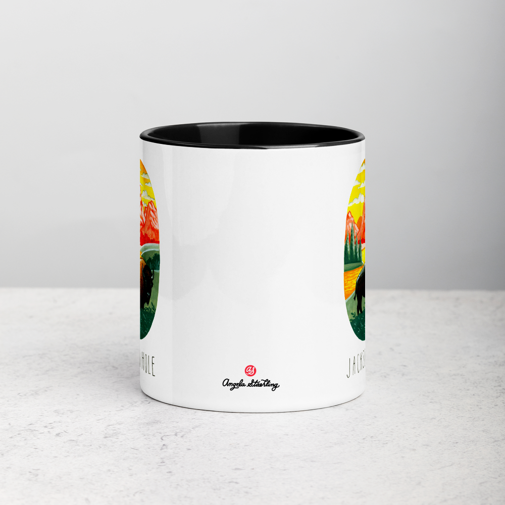 White ceramic coffee mug with black handle and inside; has Jackson Hole National Park illustration by Angela Staehling