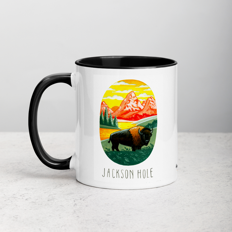 White ceramic coffee mug with black handle and inside; has Jackson Hole National Park illustration by Angela Staehling