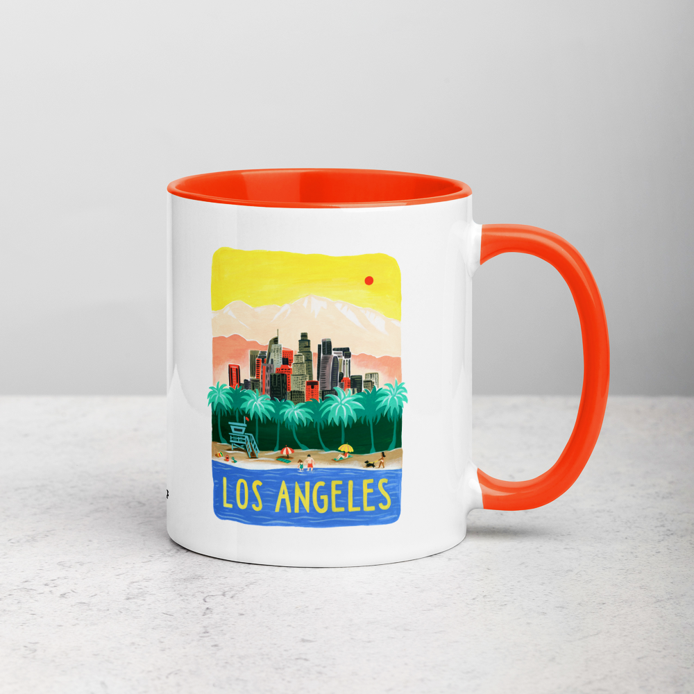 White ceramic coffee mug with orange handle and inside; has Los Angeles California illustration by Angela Staehling