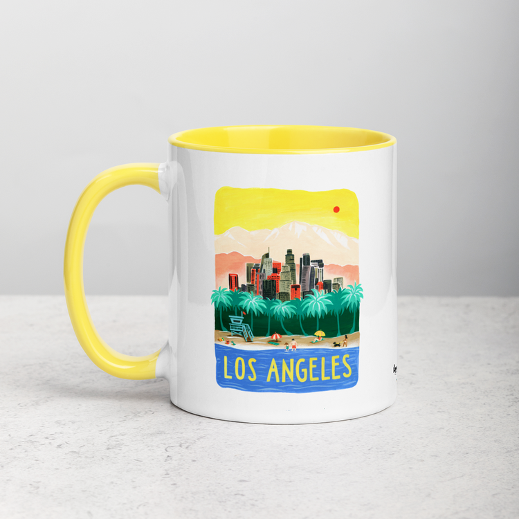 White ceramic coffee mug with yellow handle and inside; has Los Angeles California illustration by Angela Staehling