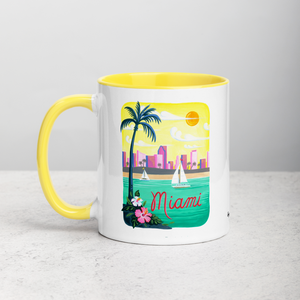 White ceramic coffee mug with yellow handle and inside; has Miami Florida illustration by Angela Staehling
