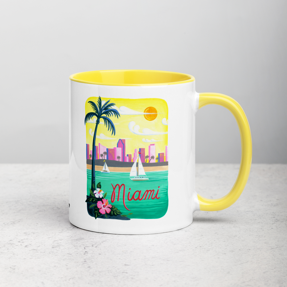 White ceramic coffee mug with yellow handle and inside; has Miami Florida illustration by Angela Staehling