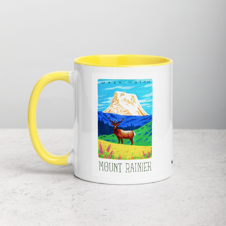 White ceramic coffee mug with yellow handle and inside; has Mount Rainier National Park illustration by Angela Staehling