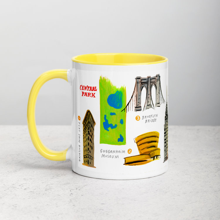 White ceramic coffee mug with yellow handle and inside; has New York landmarks illustration by Angela Staehling