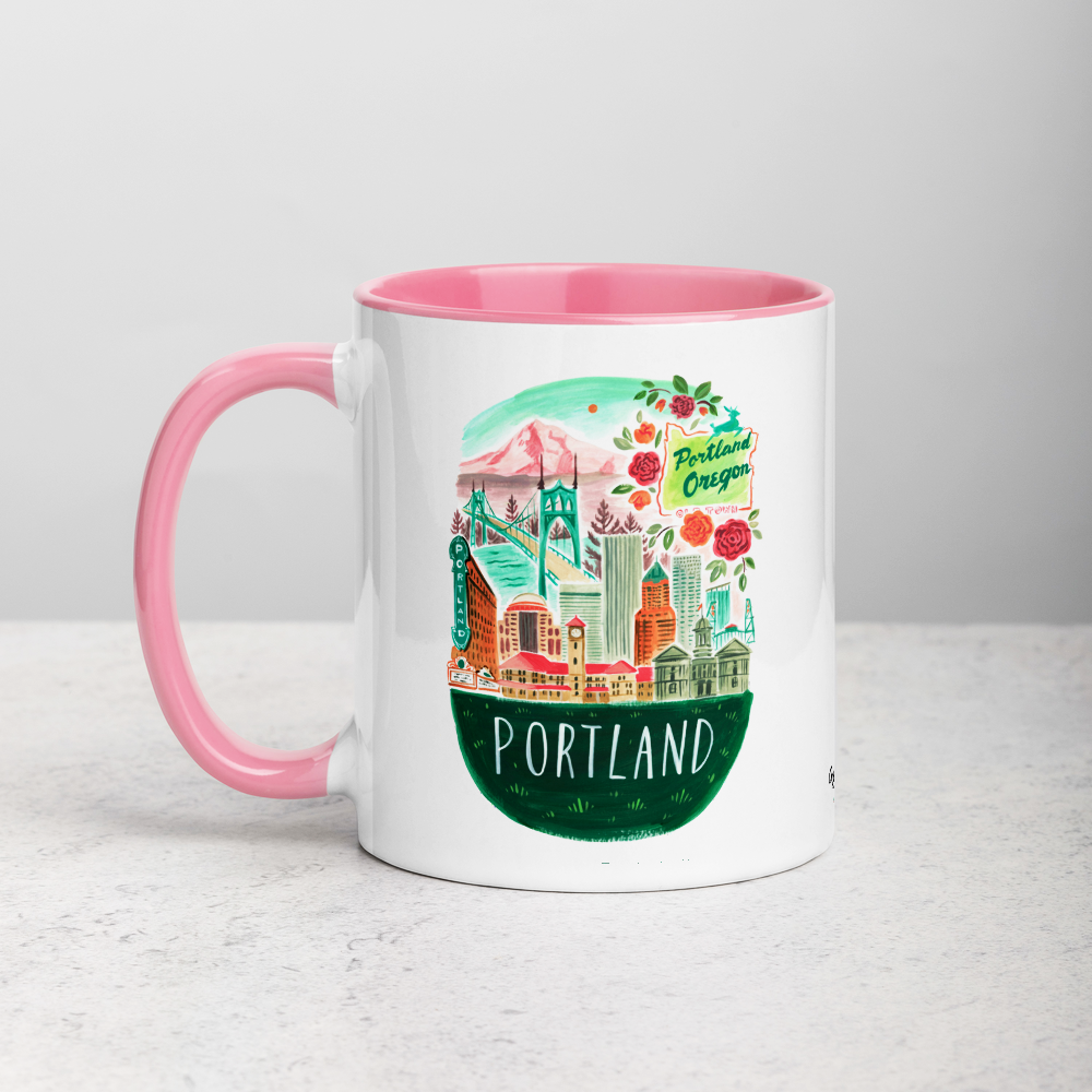 White ceramic coffee mug with pink handle and inside; has Portland Oregon illustration by Angela Staehling