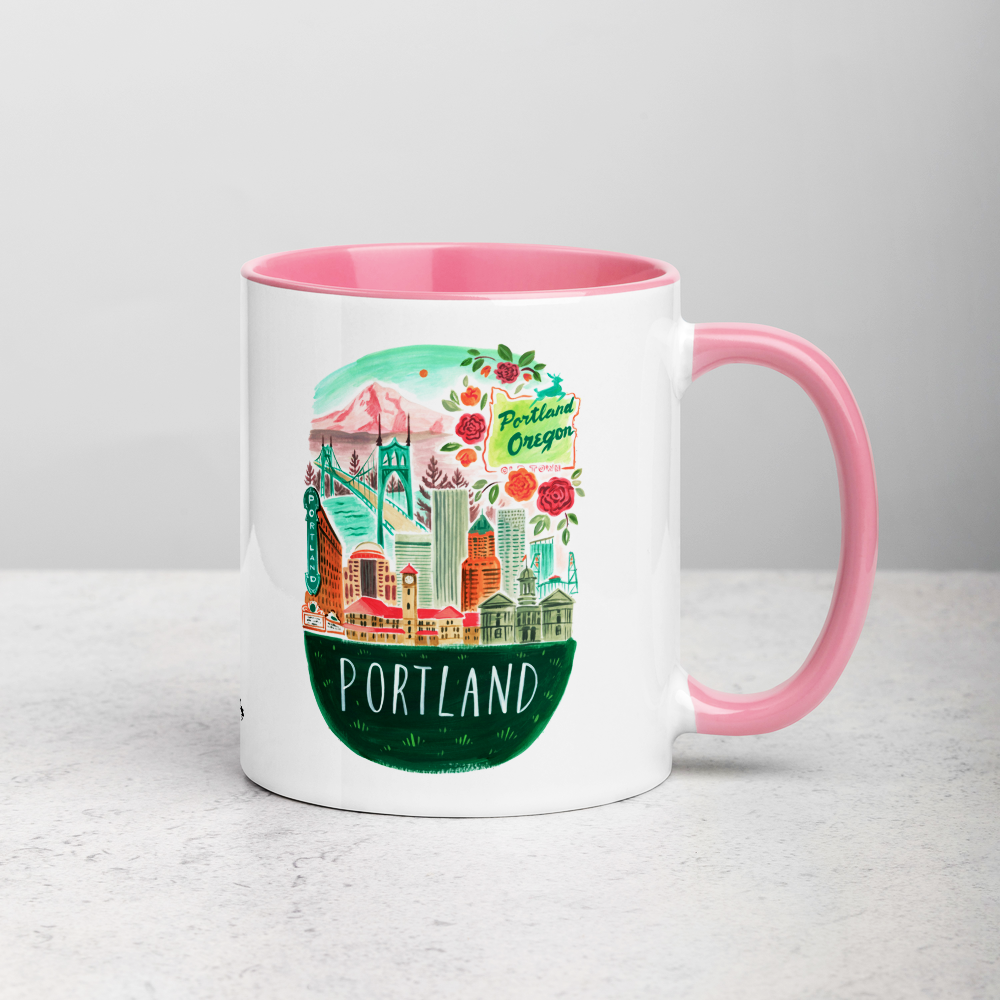 White ceramic coffee mug with pink handle and inside; has Portland Oregon illustration by Angela Staehling