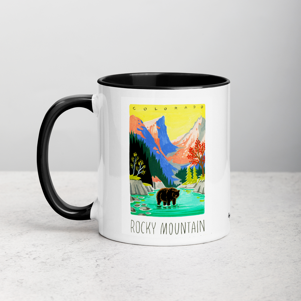 White ceramic coffee mug with black handle and inside; has Rocky Mountain National Park illustration by Angela Staehling