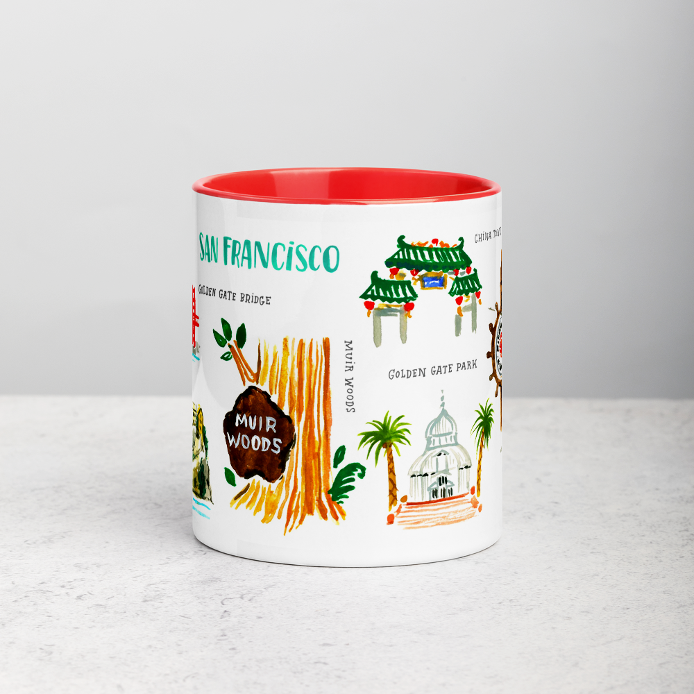 White ceramic coffee mug with red handle and inside; has San Francisco landmarks illustration by Angela Staehling