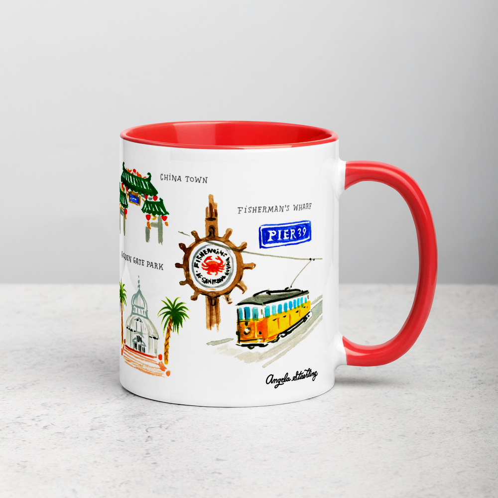 White ceramic coffee mug with red handle and inside; has San Francisco landmarks illustration by Angela Staehling