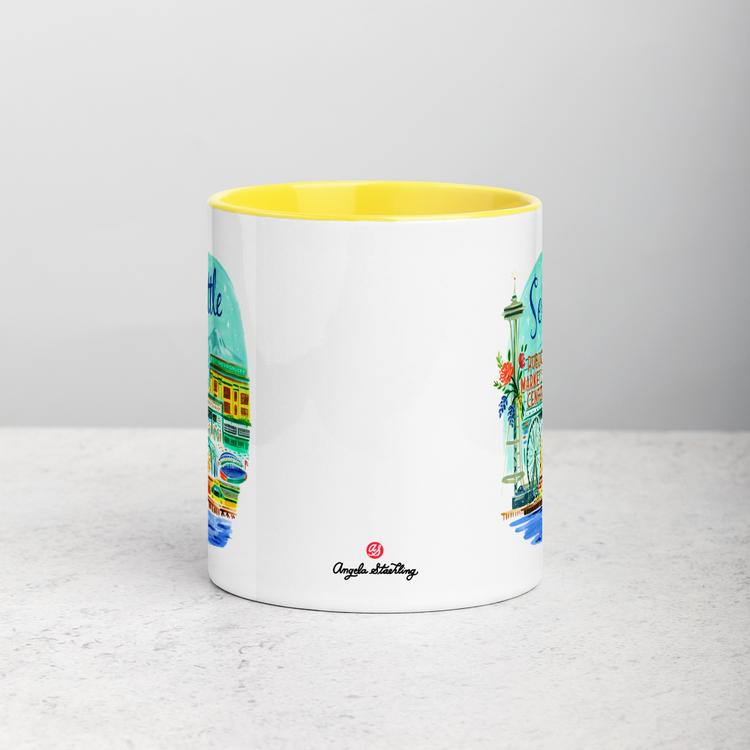 White ceramic coffee mug with yellow handle and inside; has Seattle Washington illustration by Angela Staehling