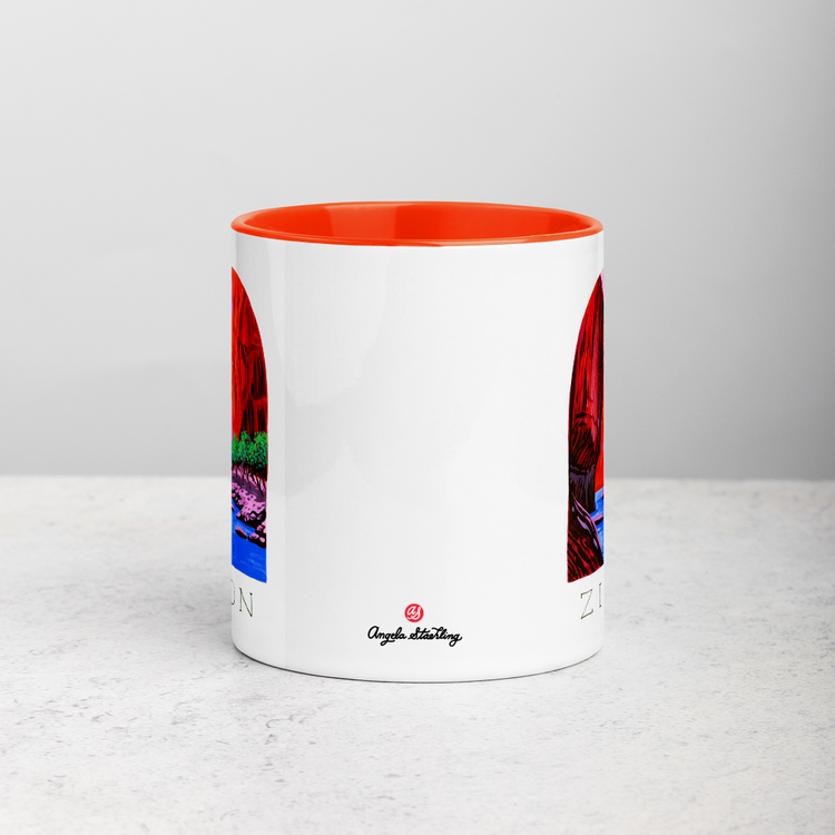 White ceramic coffee mug with orange handle and inside; has Zion National Park illustration by Angela Staehling