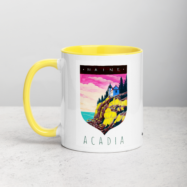 White ceramic coffee mug with yellow handle and inside; has Acadia National Park illustration by Angela Staehling