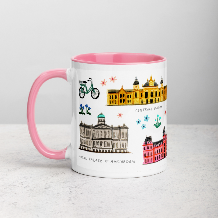 White ceramic coffee mug with pink handle and inside; has Amsterdam illustration by Angela Staehling