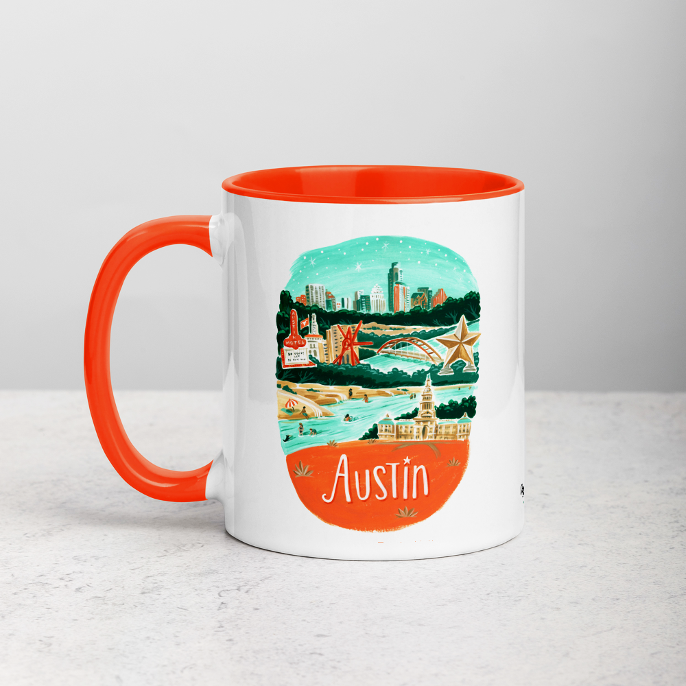 White ceramic coffee mug with orange handle and inside; has Austin illustration by Angela Staehling
