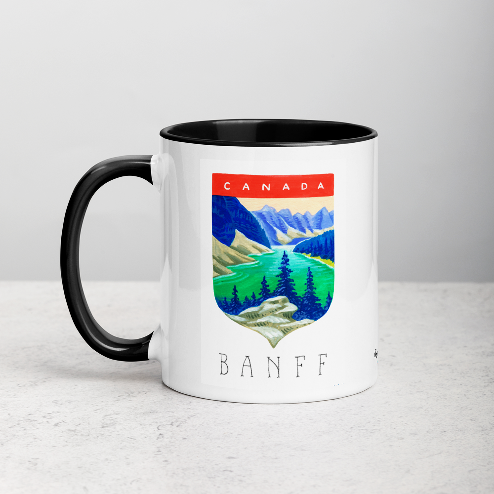 White ceramic coffee mug with black handle and inside; has Banff National Park illustration by Angela Staehling