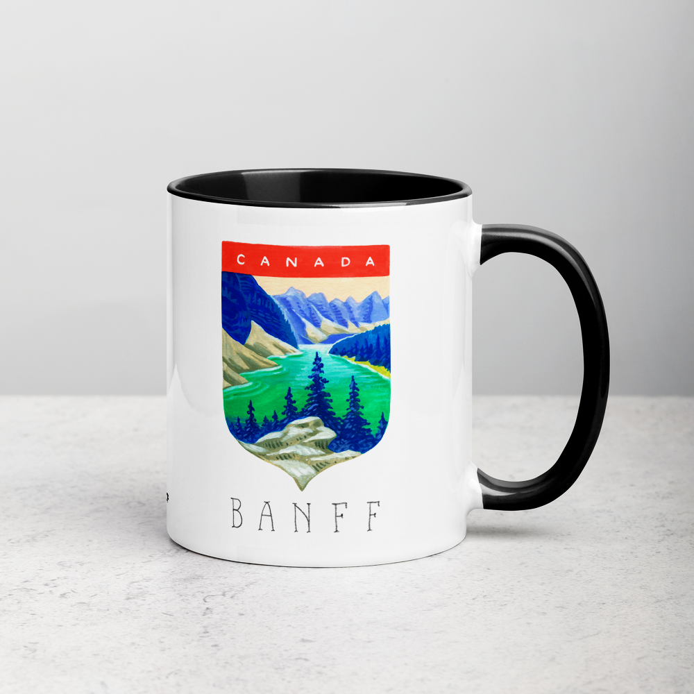 White ceramic coffee mug with black handle and inside; has Banff National Park illustration by Angela Staehling