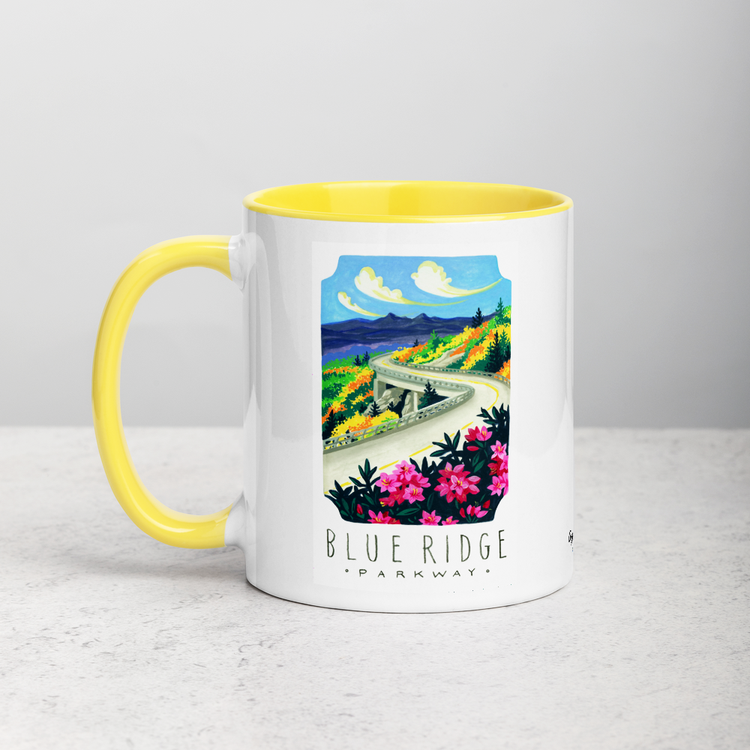 White ceramic coffee mug with yellow handle and inside; has Blue Ridge Parkway National Park illustration by Angela Staehling