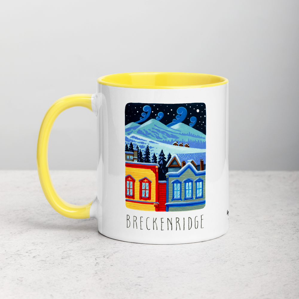 White ceramic coffee mug with yellow handle and inside; has Breckenridge illustration by Angela Staehling