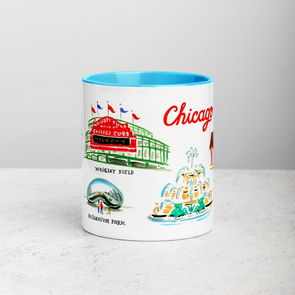 White ceramic coffee mug with blue handle and inside; has Chicago landmarks illustration by Angela Staehling