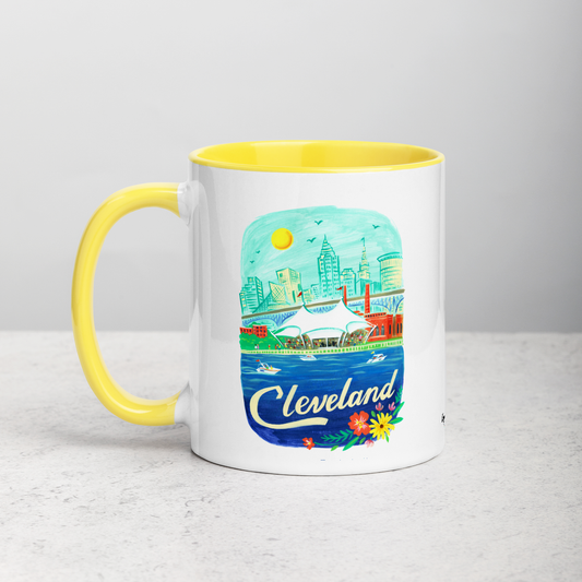White ceramic coffee mug with yellow handle and inside; has Cleveland Ohio illustration by Angela Staehling