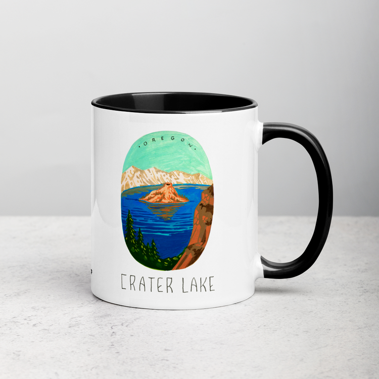 White ceramic coffee mug with black handle and inside; has Crater Lake National Park illustration by Angela Staehling