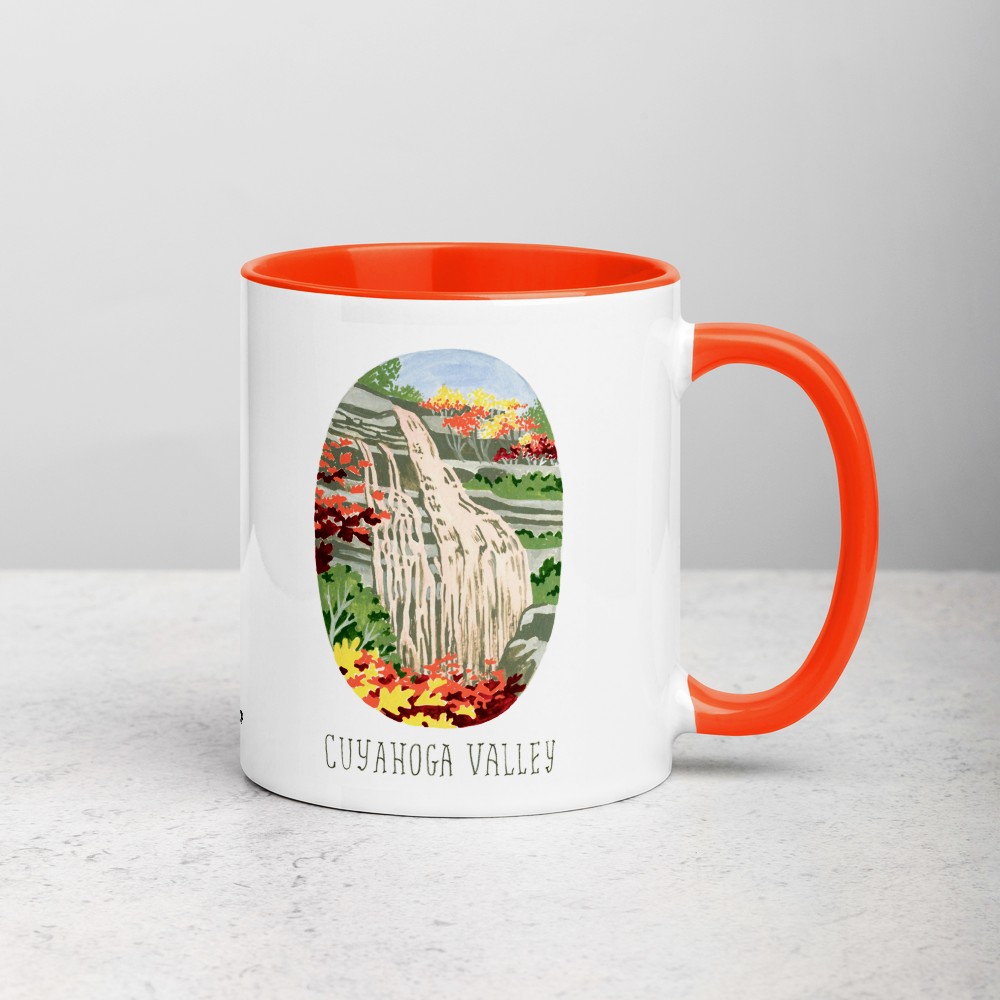 White ceramic coffee mug with orange handle and inside; has Cuyahoga Valley National Park illustration by Angela Staehling
