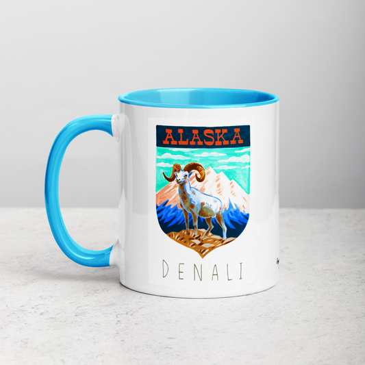 White ceramic coffee mug with blue handle and inside; has Denali National Park illustration by Angela Staehling