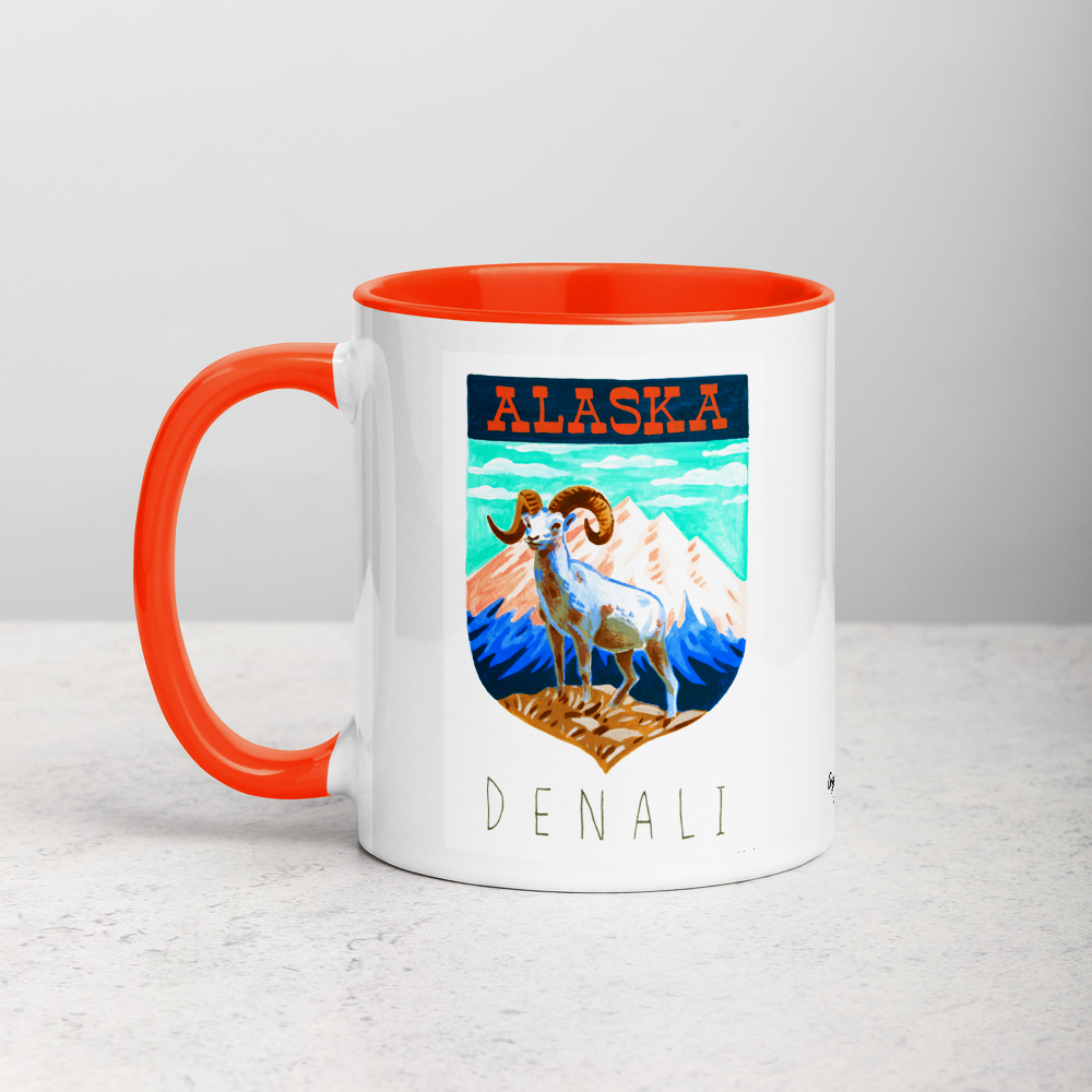 White ceramic coffee mug with orange handle and inside; has Denali National Park illustration by Angela Staehling