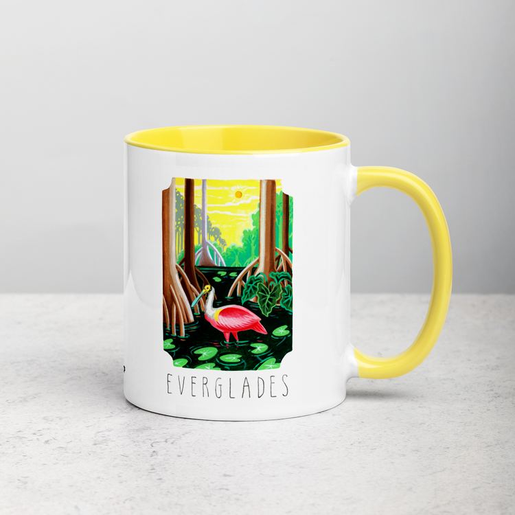 White ceramic coffee mug with yellow handle and inside; has Everglades National Park illustration by Angela Staehling