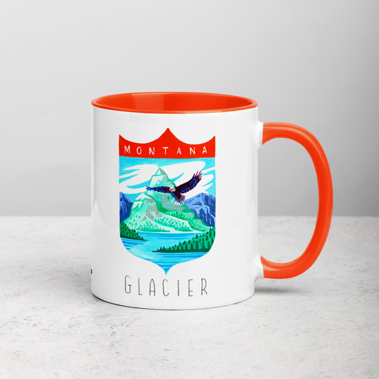 White ceramic coffee mug with orange handle and inside; has Glacier National Park illustration by Angela Staehling