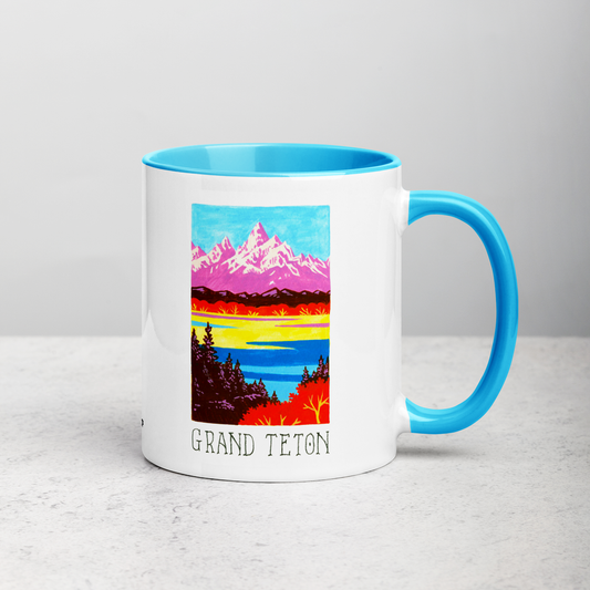 White ceramic coffee mug with blue handle and inside; has Grand Teton National Park illustration by Angela Staehling