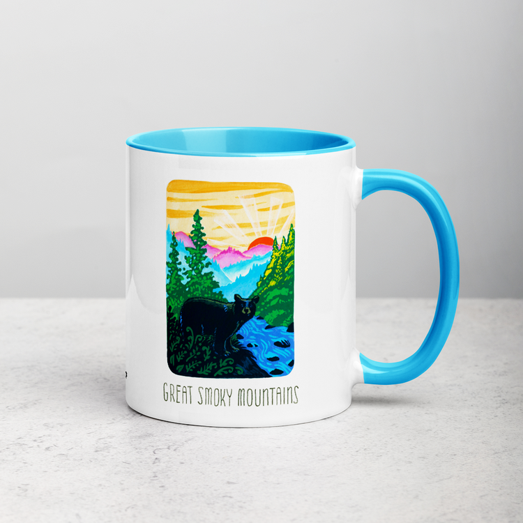 White ceramic coffee mug with blue handle and inside; has Great Smoky Mountains National Park illustration by Angela Staehling