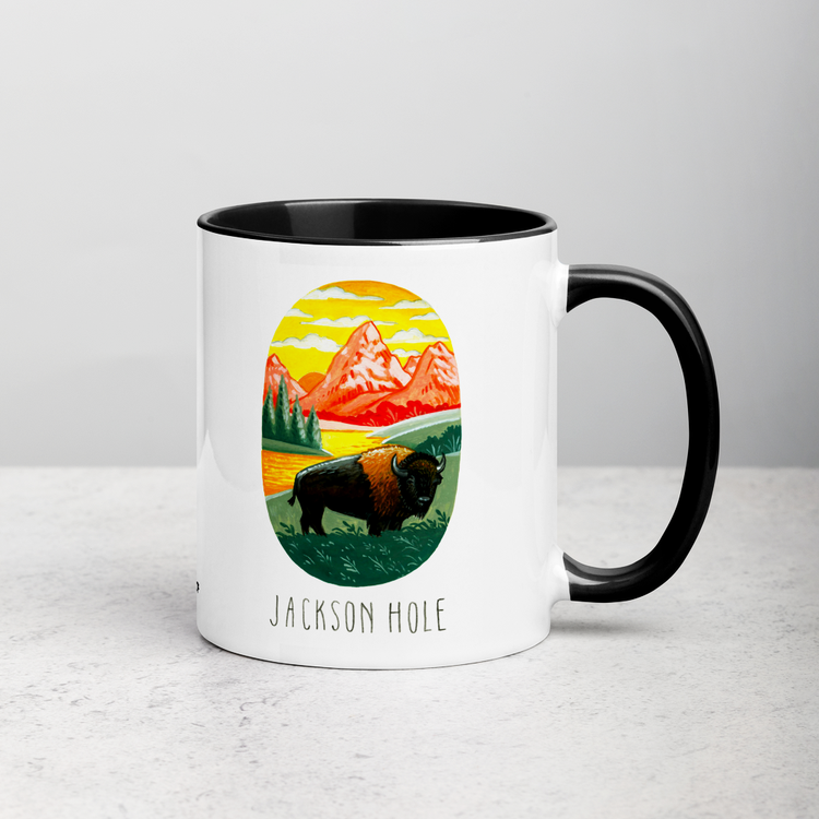 White ceramic coffee mug with black handle and inside; has Jackson Hole National Park illustration by Angela Staehling